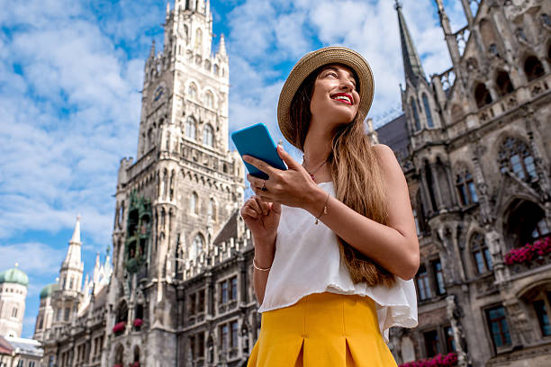 Woman traveling in Munich Young female tourist using mobile phone on the central square in front of the famous town hall building in Munich munich city hall stock pictures, royalty-free photos & images