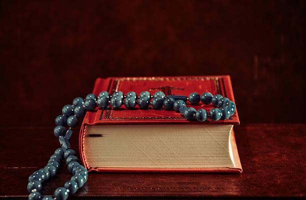 istock Rosary beads and red Holy Bible on table 615913452
