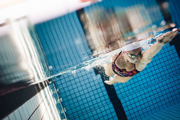 istock Female swimmer in action inside swimming pool 615915686