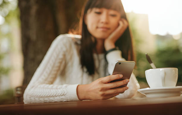 istock Young chinese woman using mobile phone at outdoor cafe 615918318