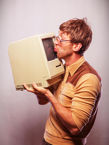 Vivid color image with retro style nerdy man kissing a 1980's computer