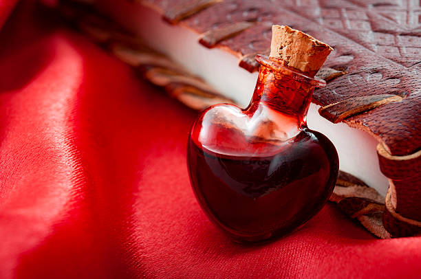 Love potion leaning on a book of spells Love potion leaning on a book of magic spells for Valentine's day alchemy photos stock pictures, royalty-free photos & images