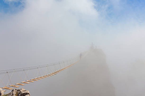 homme dans le brouillard au-dessus du gouffre - pont suspendu photos et images de collection