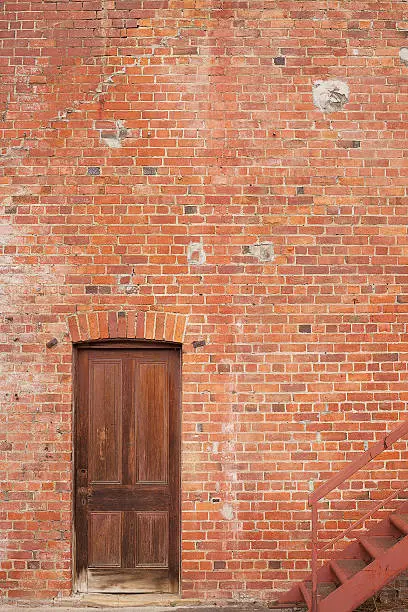 Detail of Timber door in red brick building and metal firte escape