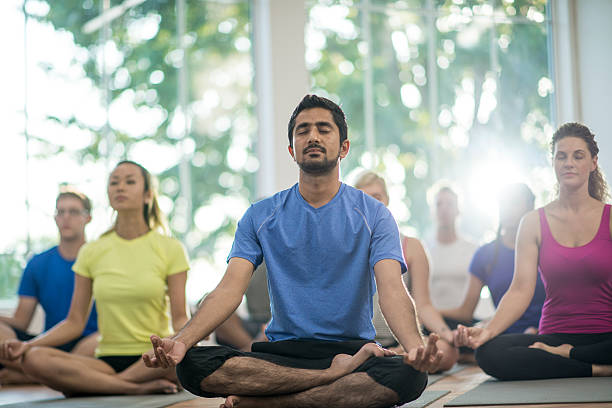 méditer tranquillement en classe - yoga men women exercising photos et images de collection