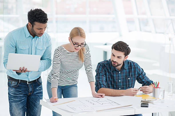 istock Group of architects discussing plans in modern office 615979682