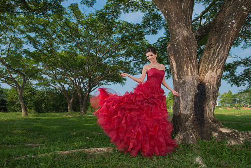 Model wearing a red evening dress in  lawn.