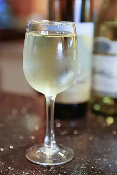 Close up view of white wine in glass with bottle in background