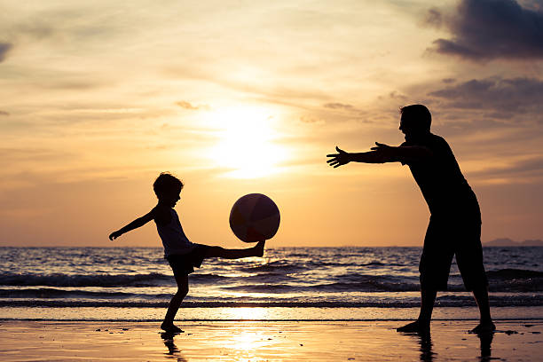 istock Father and son playing on the beach at the sunset. 615990720