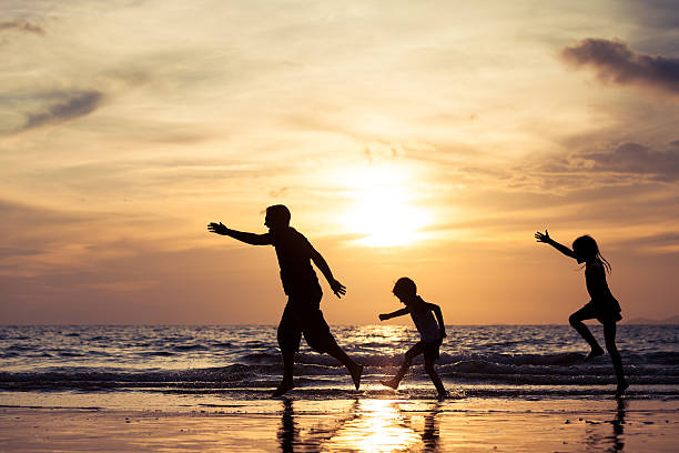 istock Father and children playing on the beach at the sunset. 615990908