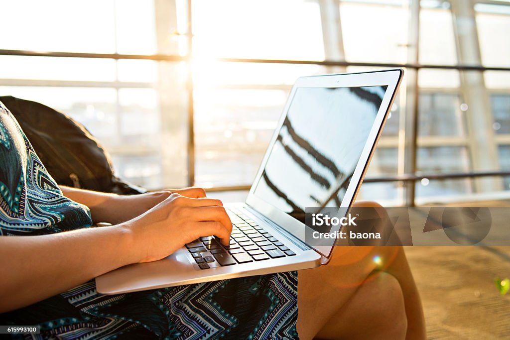 Young woman using laptop computer at airport Airport Stock Photo
