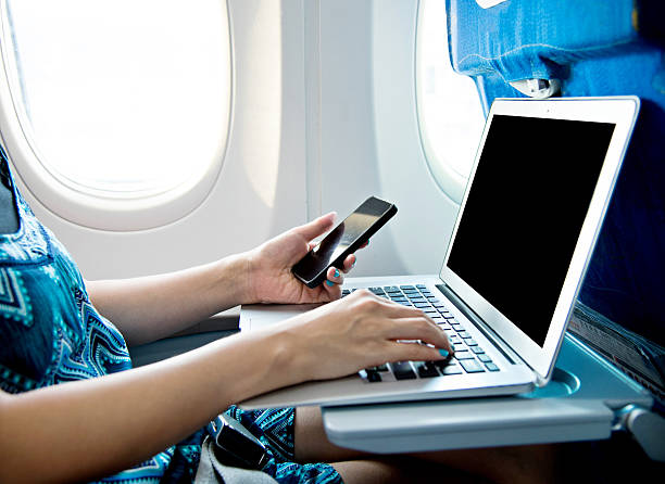 istock Woman using smart phone and laptop on airplane 615994626