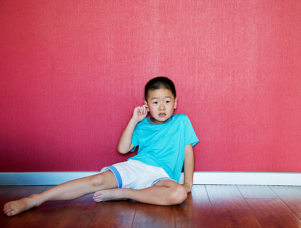 istock Little boy sitting on floor against wall 616002032