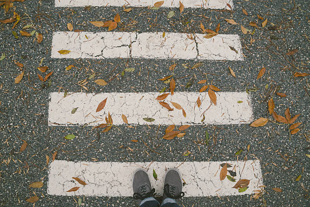 istock Pedestrian crossing covered with dry leaves. Personal perspective view. 616005678