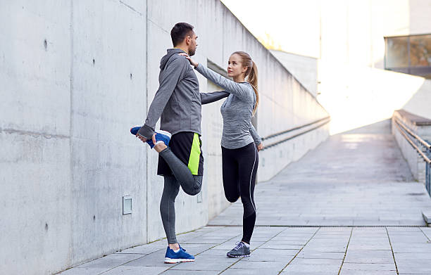 istock smiling couple stretching leg outdoors 616010244