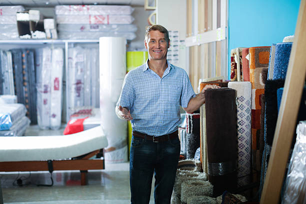 portrait of smiling man standing with carpets in household department