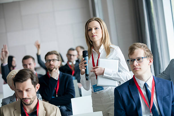 istock Confident businesswoman holding microphone while asking questions during seminar 616018388