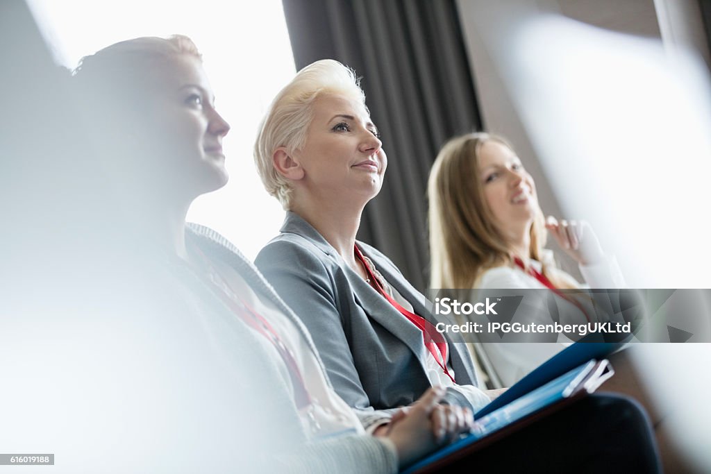 Smiling businesswomen attending seminar Convention Center Stock Photo