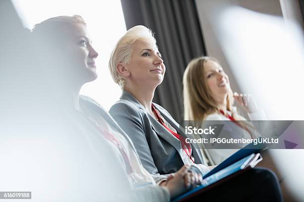 Smiling Businesswomen Attending Seminar Stock Photo - Download Image Now - Convention Center, Meeting, Attending