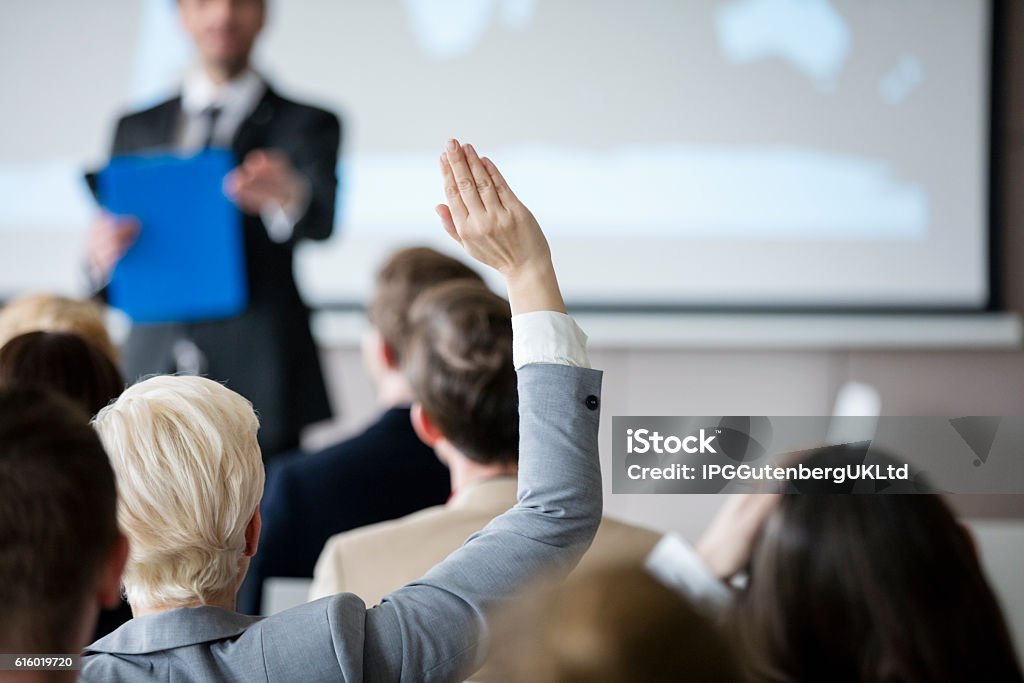 Visão traseira de empresária levantando a mão durante seminário - Foto de stock de Mão Levantada royalty-free