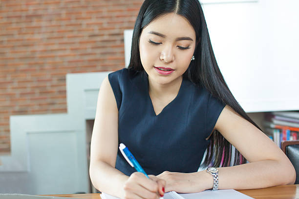 istock Beautiful Asian woman writing a notebook in modern office 616020482