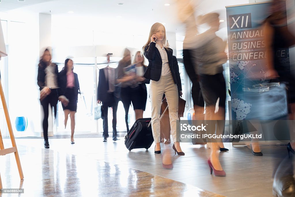Uomini d'affari con bagagli a piedi al centro congressi - Foto stock royalty-free di Immagine mossa