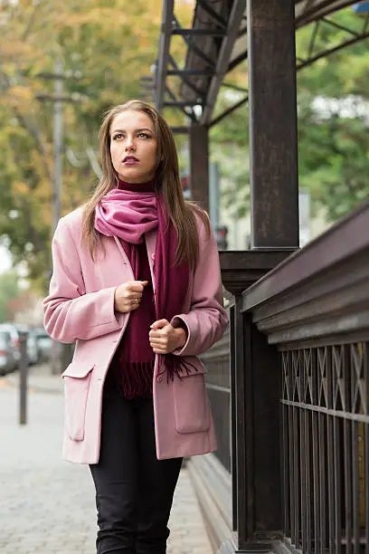 Photo of Young woman in pink topcoat at autumn day