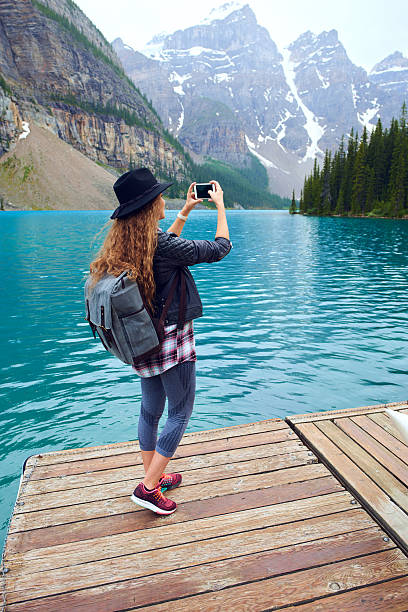 istock Young beautiful female backpacker doing pictures on her phone 616089350