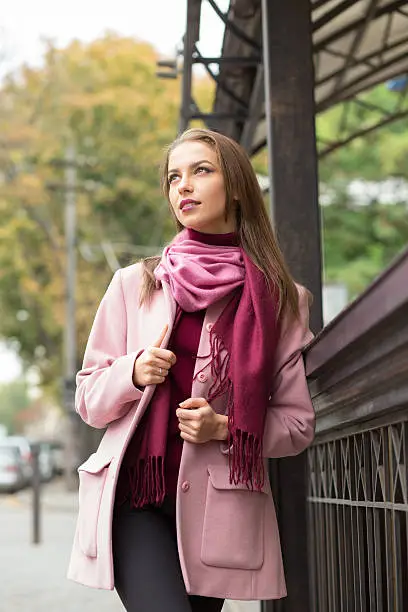 Photo of Young woman in pink topcoat at autumn day