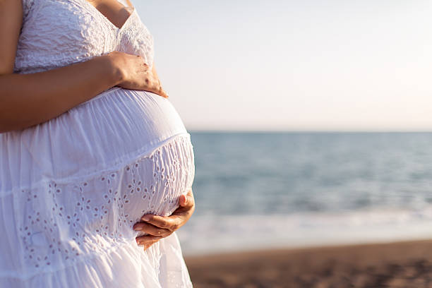 istock Young pregnant woman walking on the beach 616094170