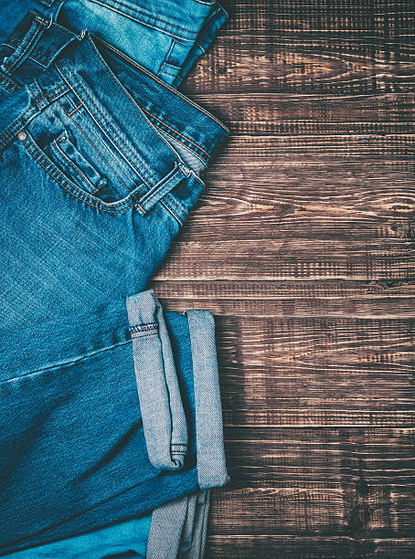 istock Blue jeans on a brown wooden background. 616094388