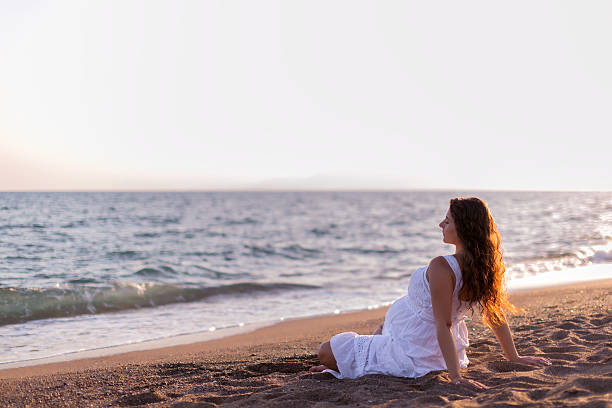 istock Young pregnant woman walking on the beach 616095212