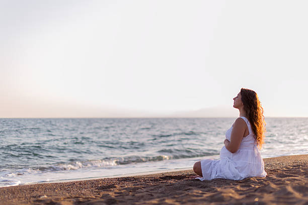 istock Young pregnant woman walking on the beach 616095304
