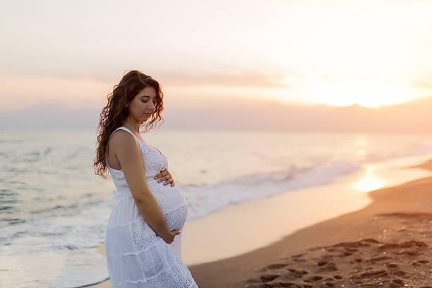 istock Young pregnant woman walking on the beach 616096862