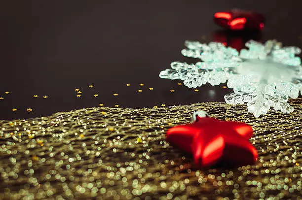 Christmas background, with red stars, translucent snowflake, golden star-shaped glitter and golden ribbon.