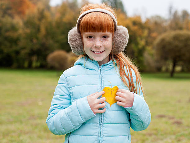 istock Little ginger girl holding a heart shaped leaf 616097742