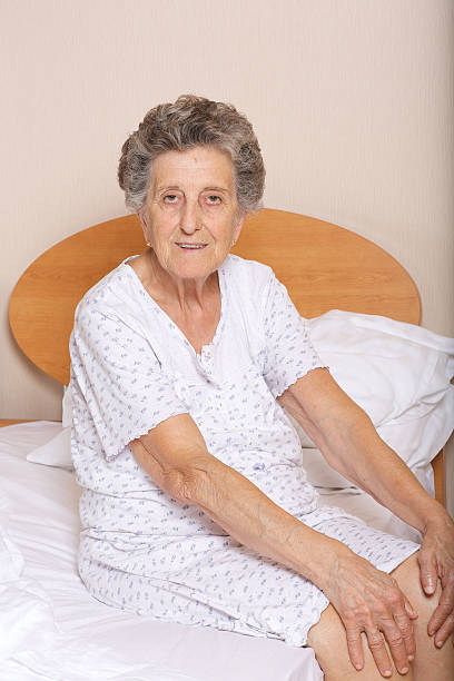 старшая женщина сидит в своей постели - respect women human teeth people стоковые фото и изображения