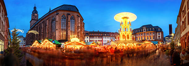 Christmas market in Heidelberg, Germany Christmas market in Heidelberg, Germany, a panorama shot at dusk showing illuminated kiosks, historic architecture and blurred people heidelberg germany stock pictures, royalty-free photos & images