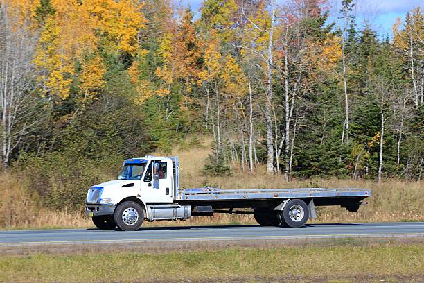 istock Flat bed tow truck on a highway. trees in background 616108362