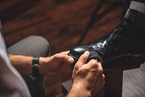 careful artisan taking care of shoes man cleaning dirt from footwear with a wet rag, close up brogue photos stock pictures, royalty-free photos & images