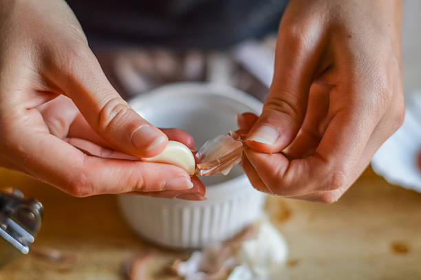 peeling knoblauch, um eine kochsauce zu machen - hautnah - schälen essen zubereiten stock-fotos und bilder