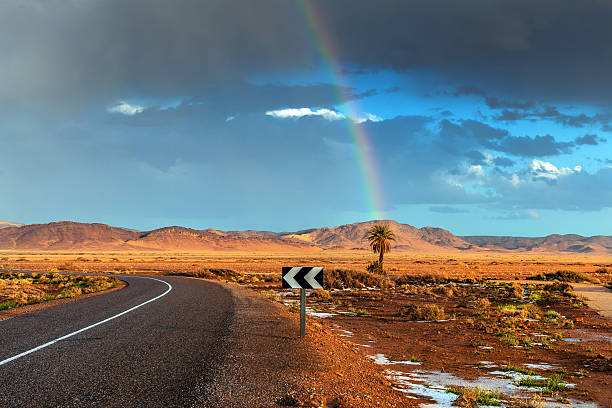 tempesta con un arcobaleno sopra la strada nel deserto - mini van ecosystem dramatic sky meteorology foto e immagini stock