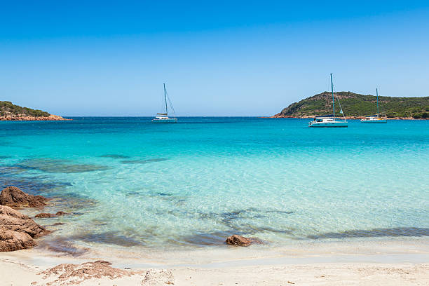 Boats mooring in the turquoise water of  Rondinara beach Corsica stock photo