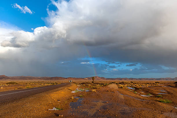 tempesta con un arcobaleno sopra la strada nel deserto - mini van ecosystem dramatic sky meteorology foto e immagini stock