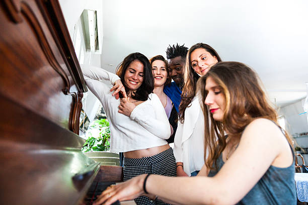 Friends playing piano together during a party at home