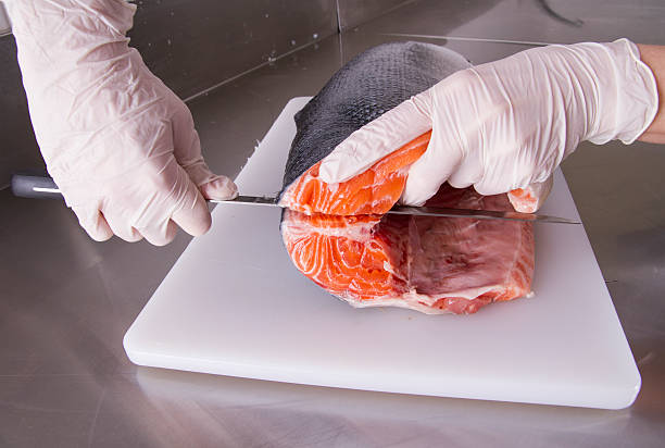 Cook cut up raw fish in kitchen