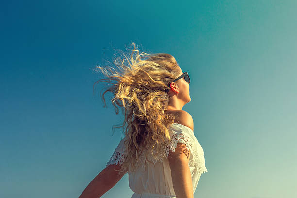 ventosa en el pelo chica de ensueño con sunflare en la playa - modelo de artista fotografías e imágenes de stock