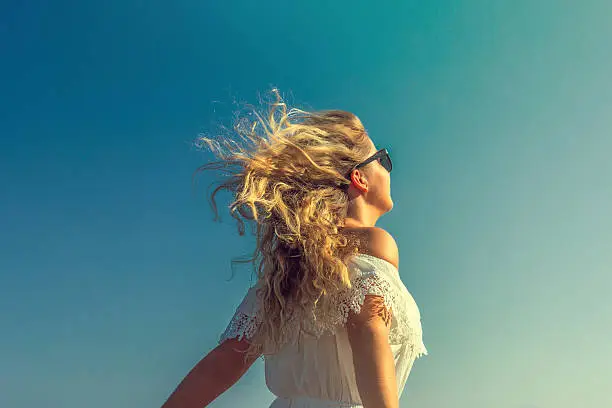 Photo of windy in hair dreamy girl with sunflare on beach