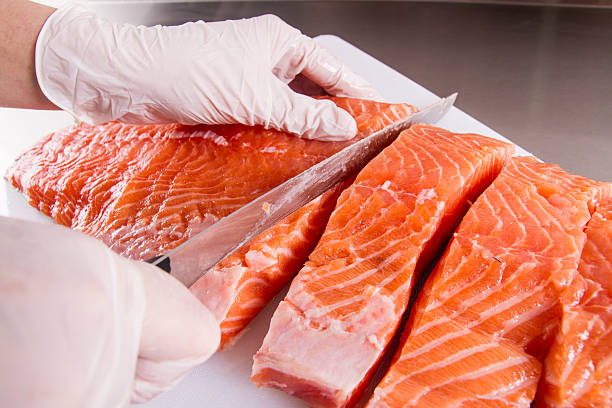 Cook cut up raw fish in kitchen