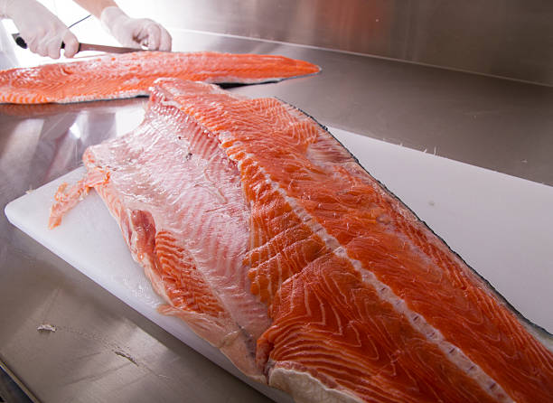 istock Cook cut up raw fish in kitchen 616115278